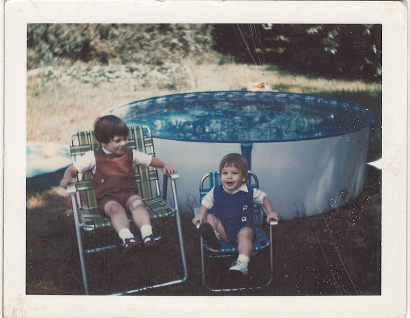 Young children sitting in lawn chairs next to pool